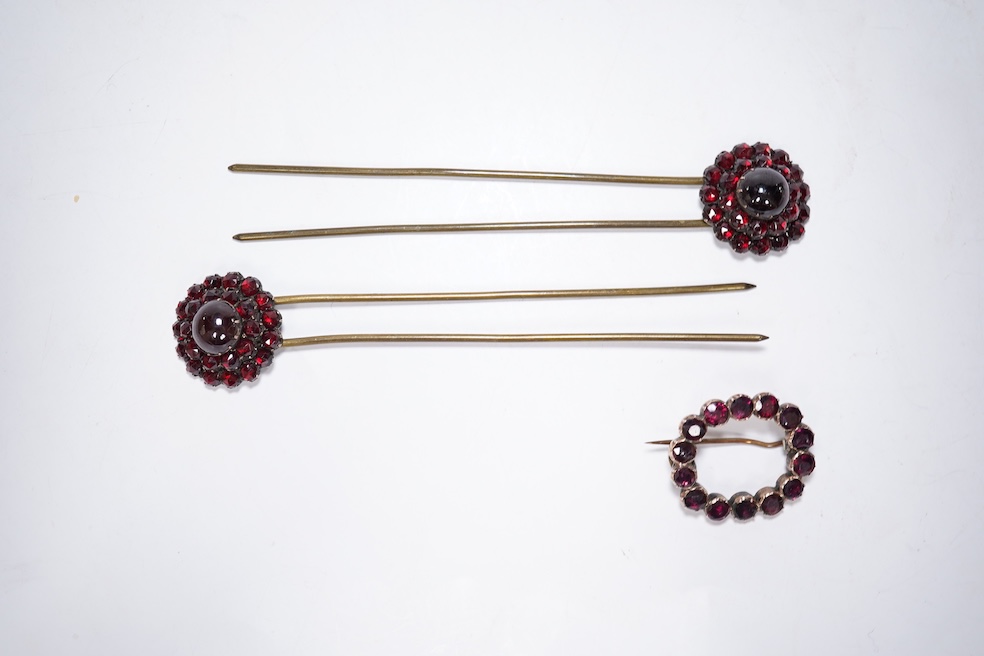A Victorian yellow metal and garnet cluster set open work brooch, 27mm, together with two garnet cluster set hair ornaments. Condition - poor to fair